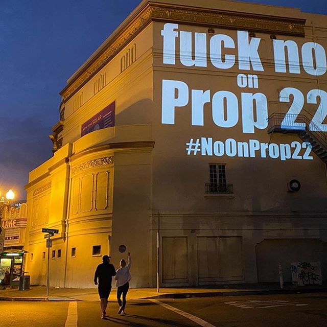 Fuck No on Prop 22 projected on the side of a building.