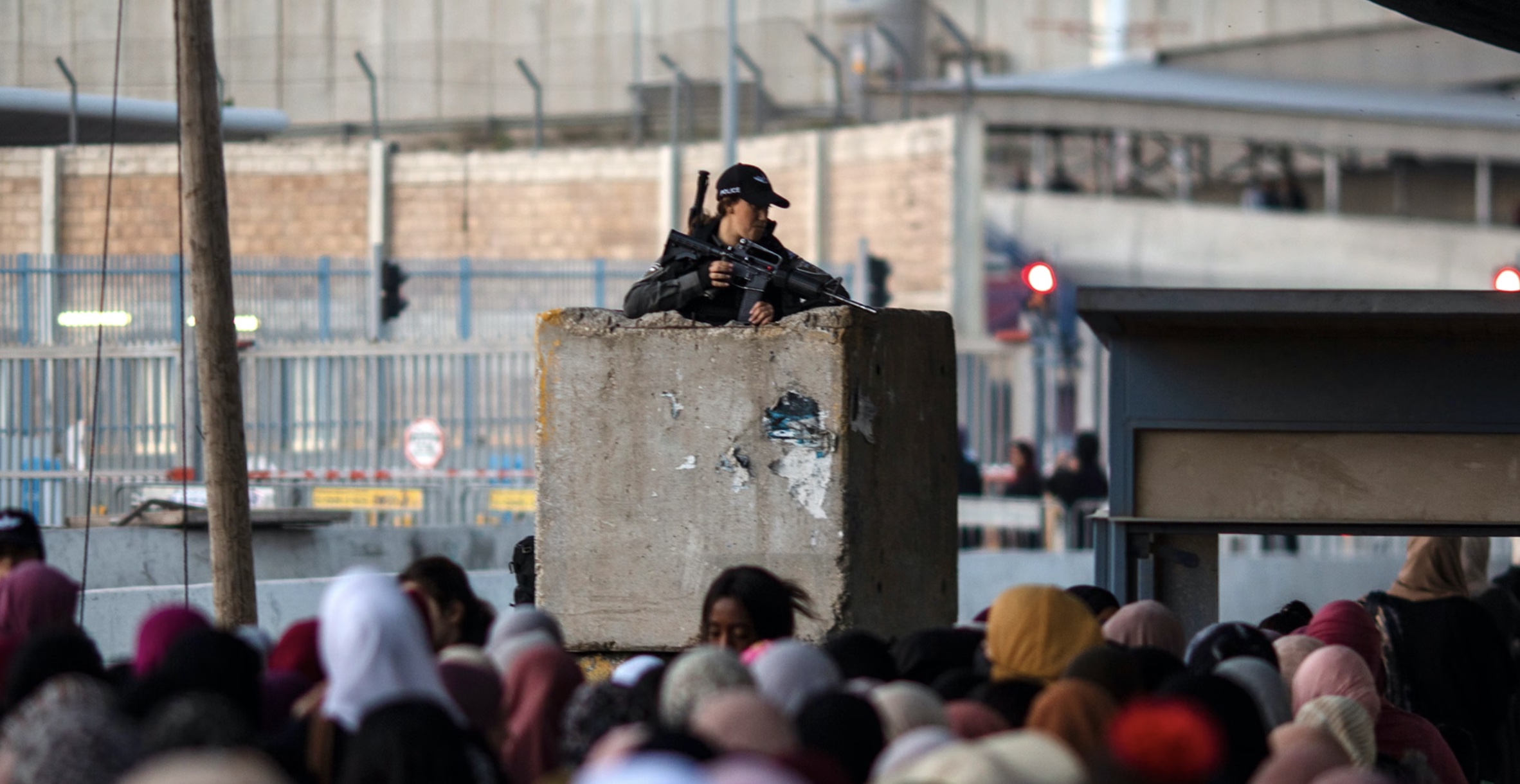 An Israeli border police stands guard as Palestinians make their way through Qalandia checkpoint
